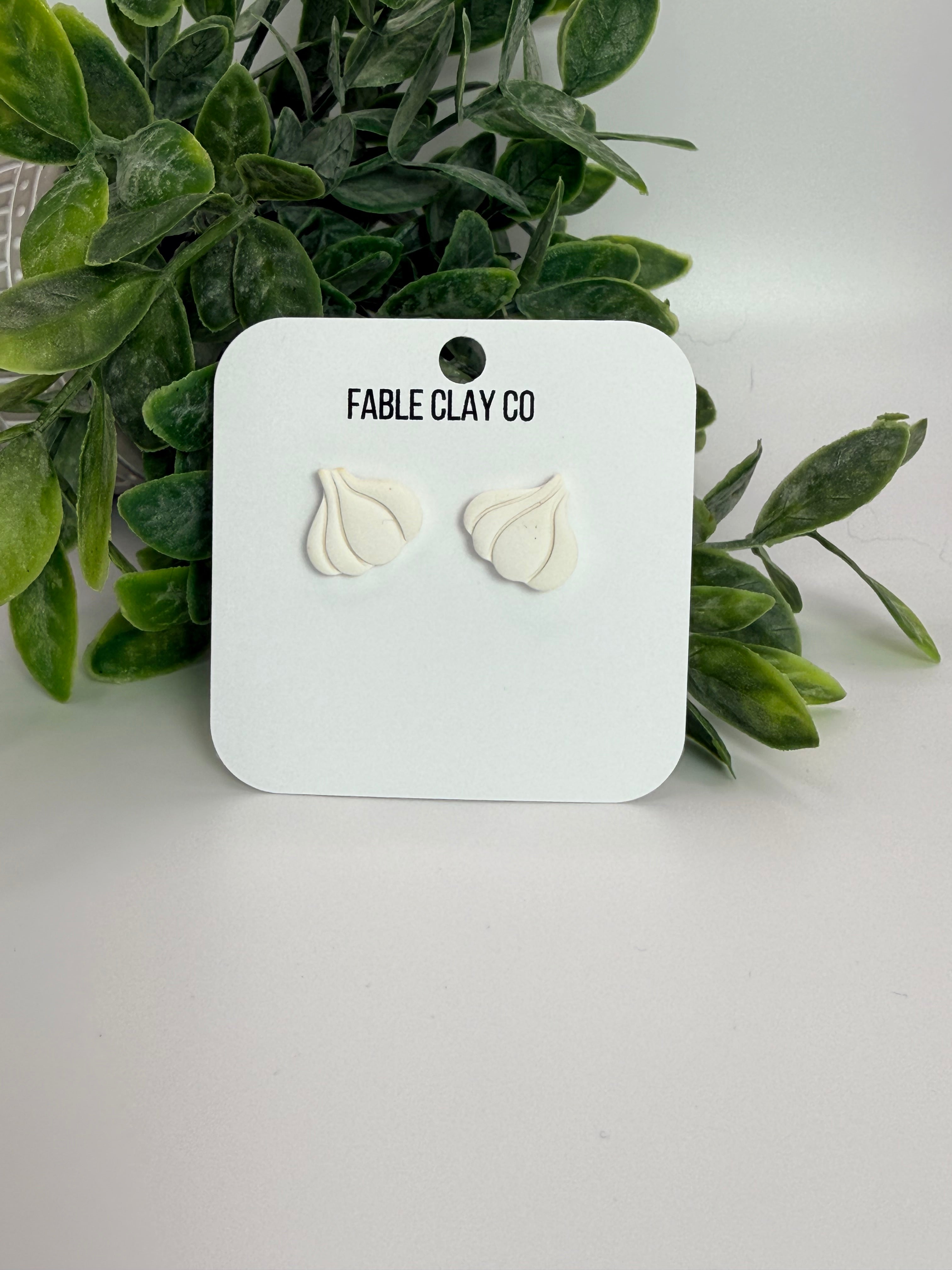Fresh garlic bulbs from Fable Clay Co displayed on a neutral surface, showcasing their textured outer skins.
