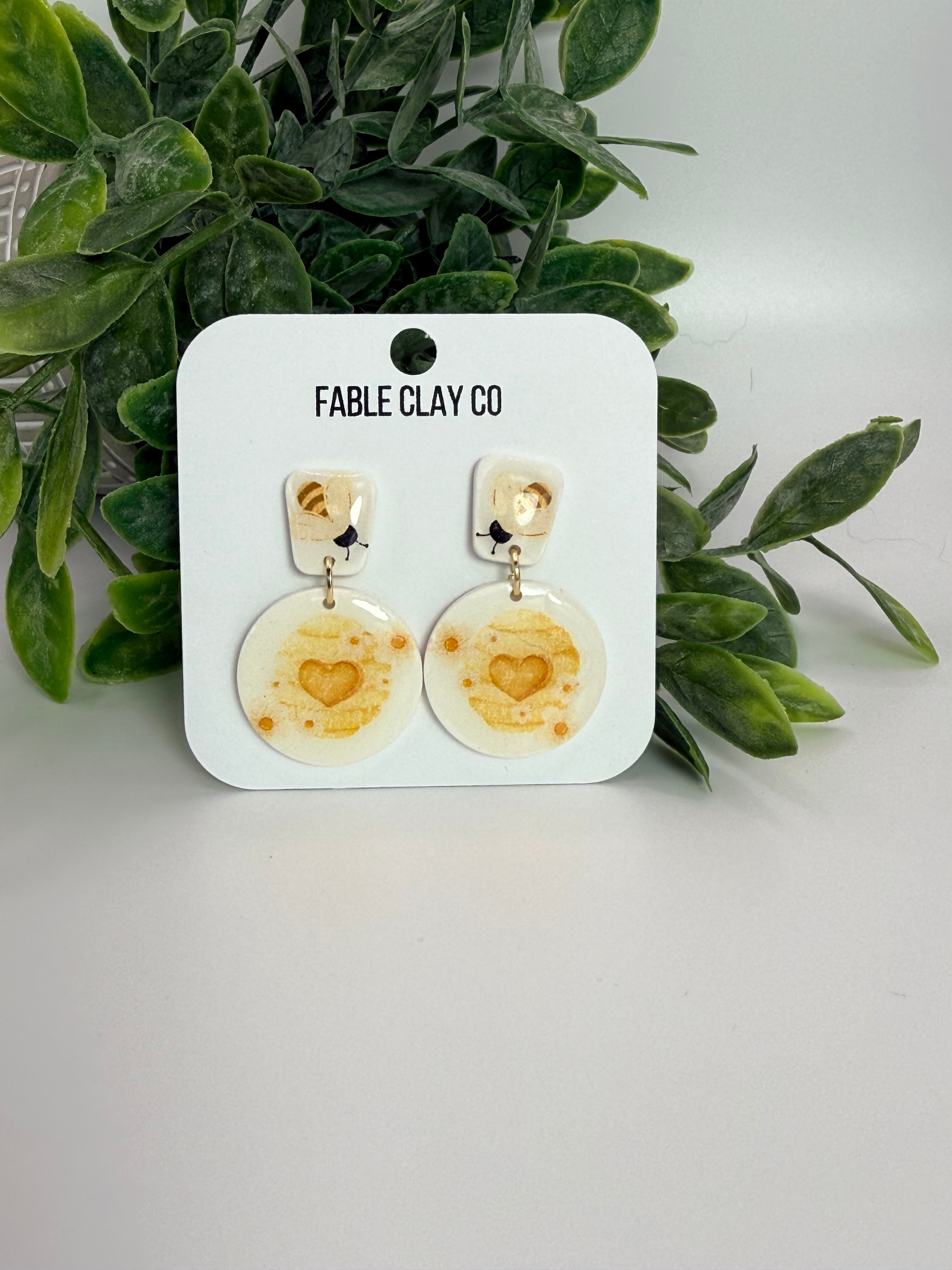 Fable Clay Co honey jar with wooden honey dipper, showcasing golden honey inside a glass container on a wooden surface.