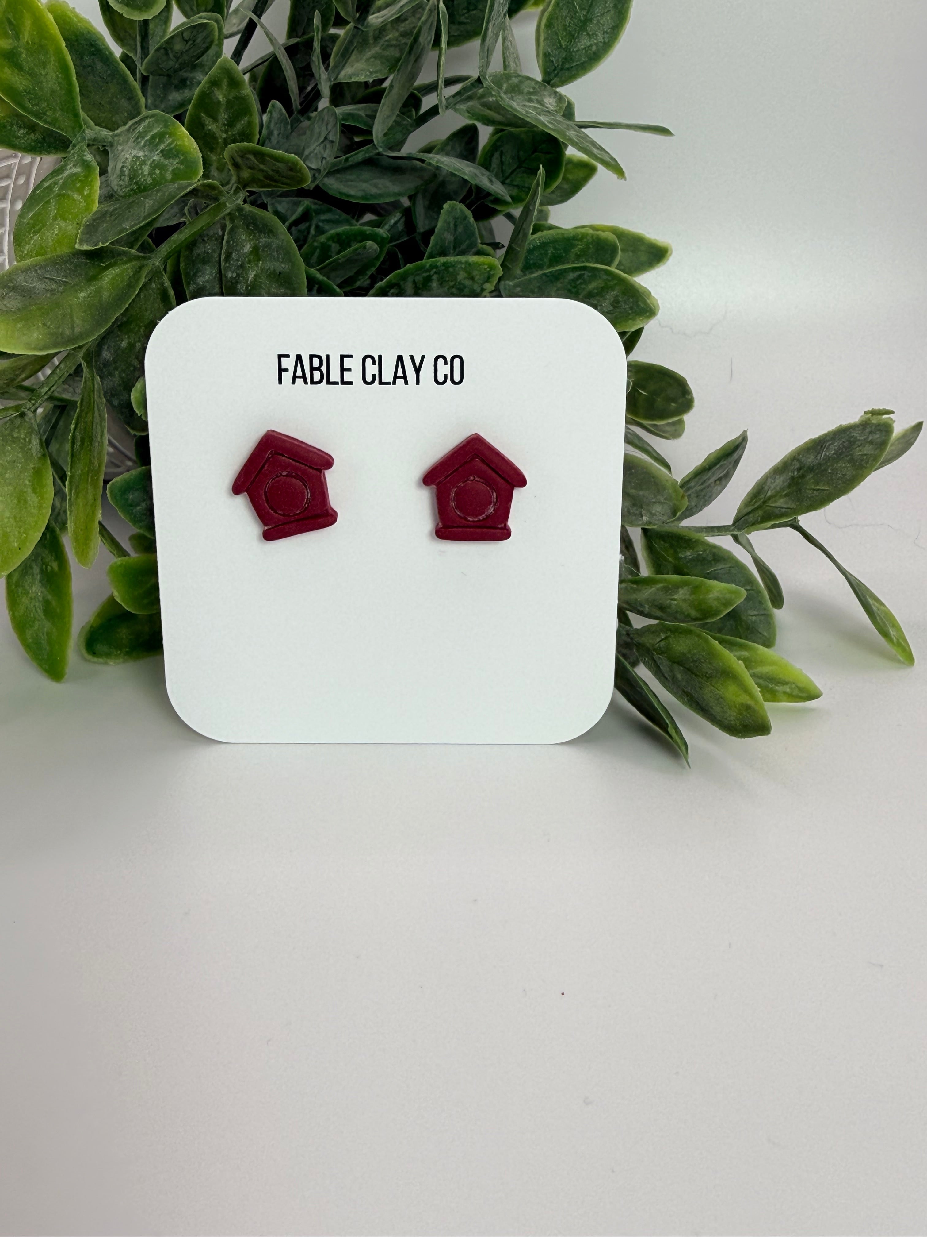Fable Clay Co bird house with wooden perch and roof, designed for outdoor use and attracting small songbirds.