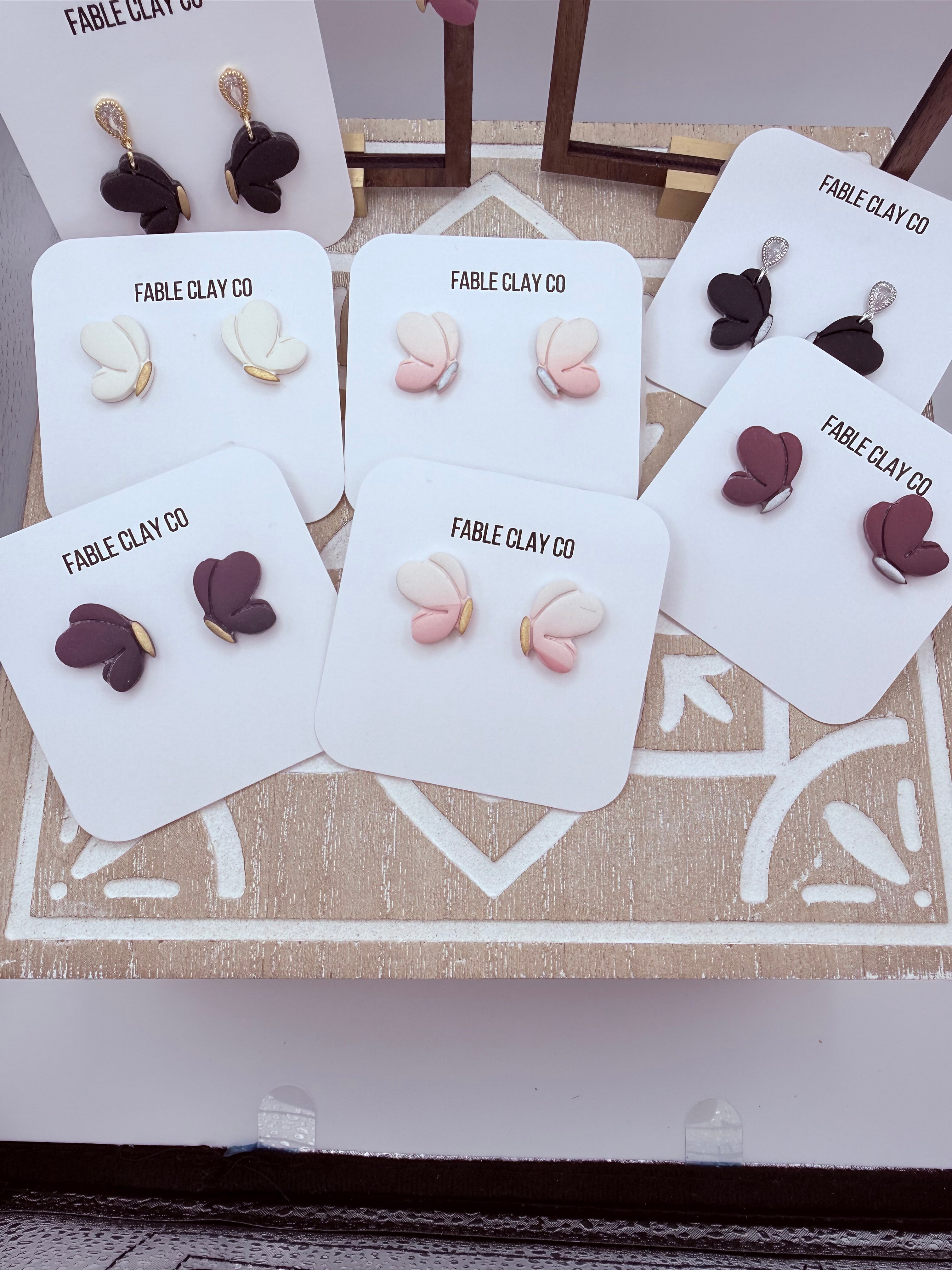 Lightweight handmade butterfly earrings by Fable Clay Co, made of colorful polymer clay with detailed wing designs.