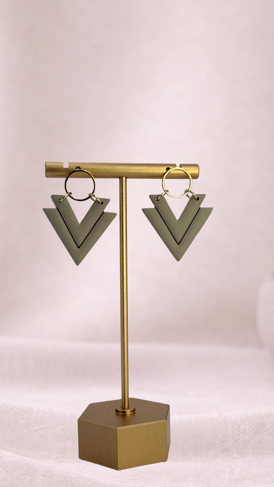 Sage green triangle-shaped earrings on a gold stand.