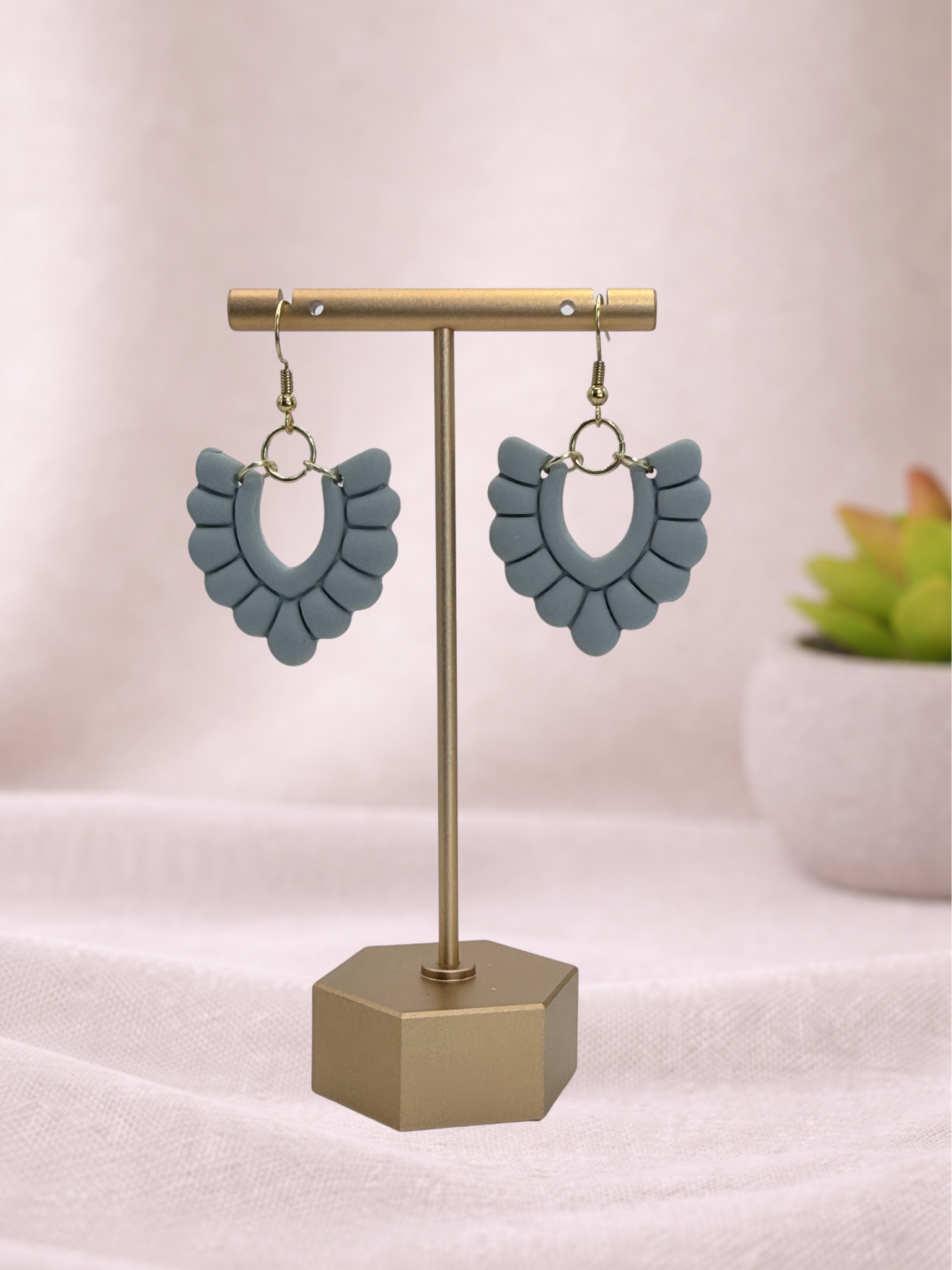 Blue earrings on a gold stand with a white background