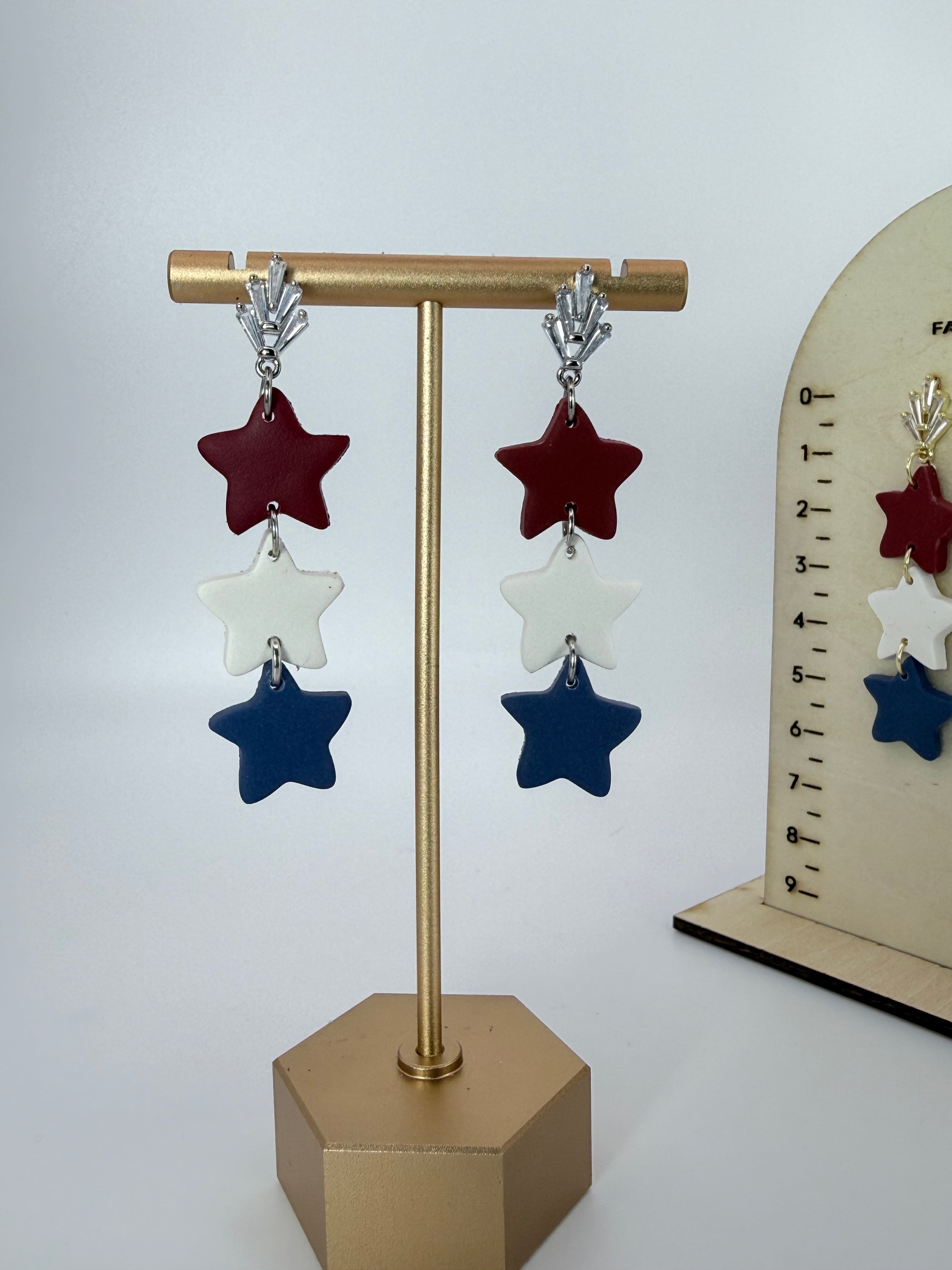 Star-shaped earrings on a gold stand with a white background